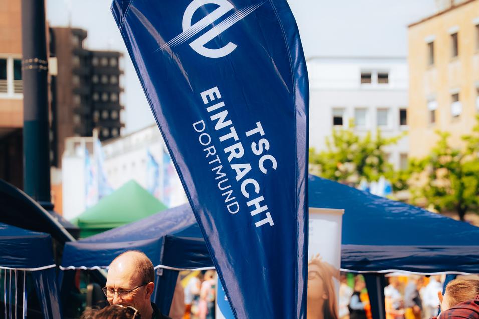 Wimpel des TSC Eintracht Dortmund steht am Informationsstand auf einem belebten Platz bei Veranstaltungen.