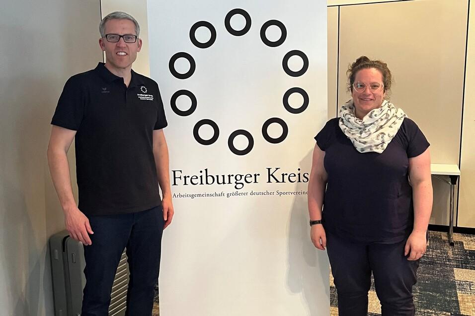 Zwei Personen stehen neben einem Banner des Freiburger Kreises in einem hellen Raum.