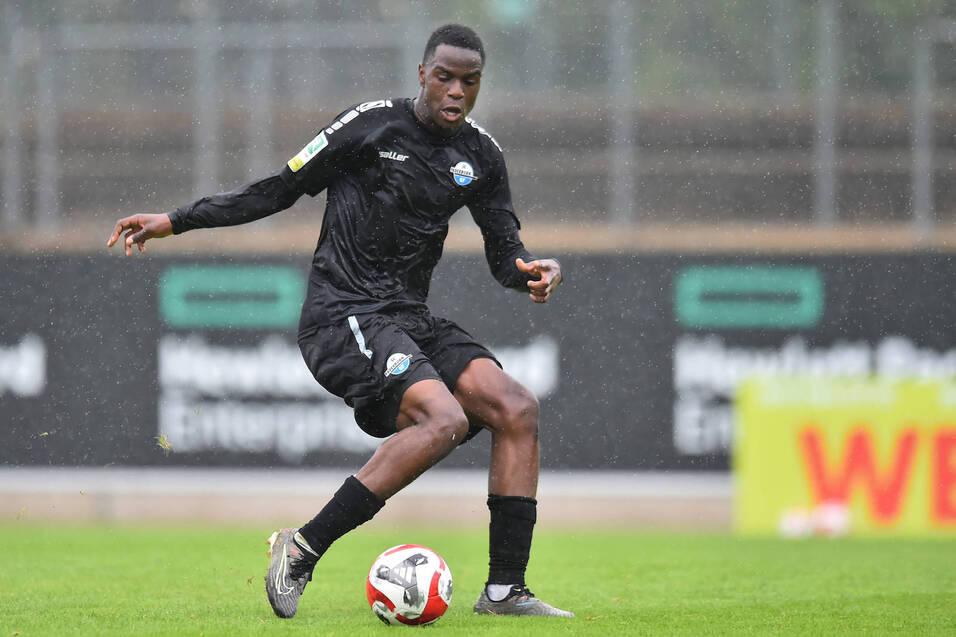 Junger Fu&szlig;ballspieler in schwarzer Ausr&uuml;stung, dribbelt den Ball bei Regen auf einem Trainingsplatz.