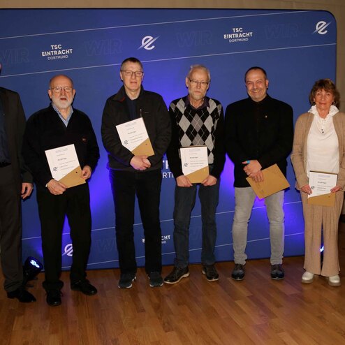 Gruppe von sechs Personen bei einer Preisverleihung, alle halten Urkunden in der Hand, vor einem blauen Hintergrund.