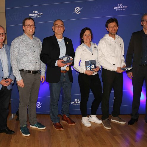 Gruppenbild von sechs Personen, die Preise in H&auml;nden halten, vor einem blauen Hintergrund mit dem Logo des TSC Eintracht.
