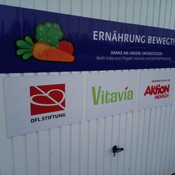 Wand mit einem Banner &bdquo;Ern&auml;hrung bewegt!&ldquo; und Logos von DFL Stiftung, Vitavia und Aktion Mensch.