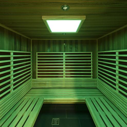 Innenansicht einer Sauna mit Holzbank und grünem Licht, umgeben von Holzleisten an den Wänden.