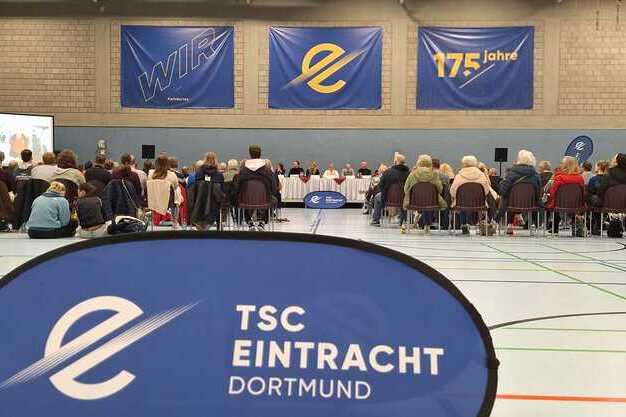 Versammlung des TSC Eintracht Dortmund in einer Sporthalle, mit vielen Teilnehmern, einem Podium und dekorativen Bannern.