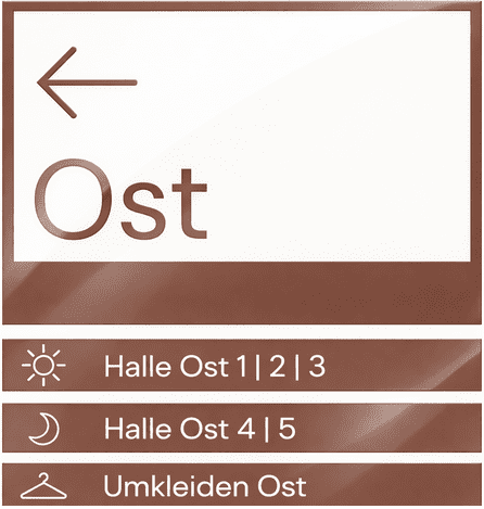 Wegweiser mit Richtungspfeil nach links, der auf &bdquo;Ost&ldquo; und Hallen sowie Umkleiden hinweist.