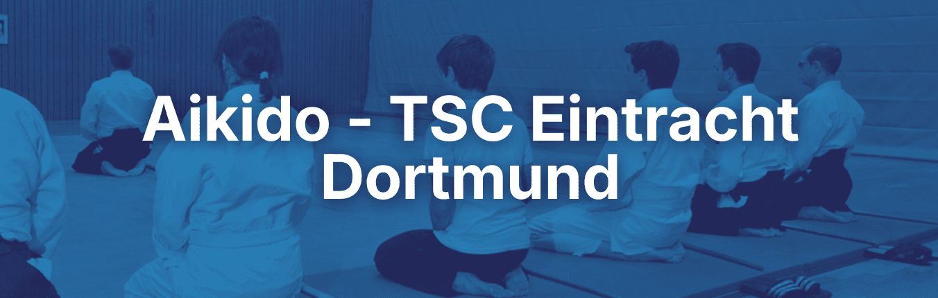 Sitzende Aikido-Praktizierende in weißer Kleidung auf Tatami-Matten in einem Übungsraum.