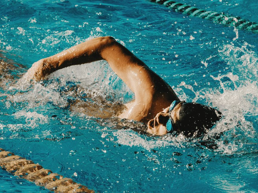 Schwimmer in einer Bahn vollbringt einen Kraularmzug im blauen Wasser eines Schwimmbeckens.