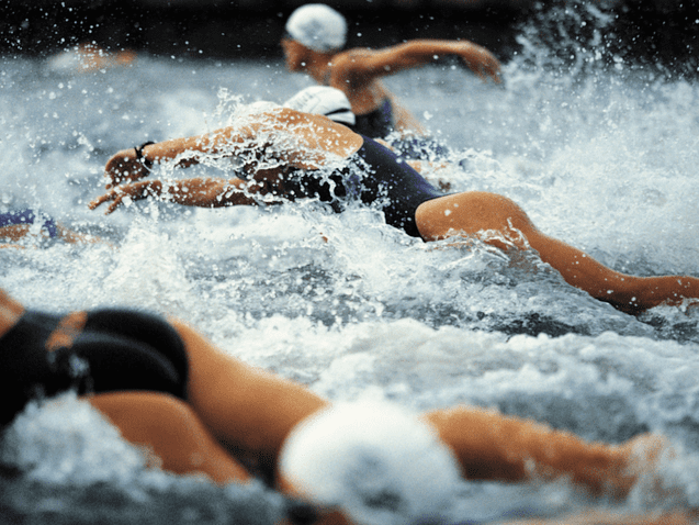 Gruppenschwimmer in einem Wettkampf spritzen Wasser w&auml;hrend des Wettkampfs im offenen Gew&auml;sser.