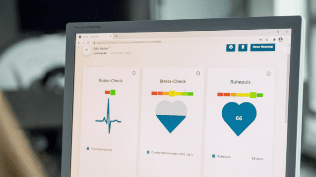 Monitor zeigt Gesundheitsdaten: Risiko-Check, Stress-Check und Ruhestellen mit Herzsymbol und Werten auf dem Bildschirm.