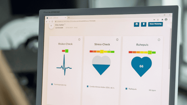 Monitor zeigt Gesundheitsdaten: Risiko-Check, Stress-Check und Ruhestellen mit Herzsymbol und Werten auf dem Bildschirm.