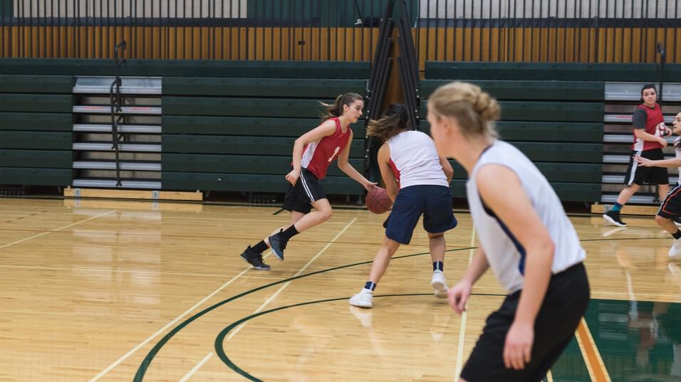 Zwei Basketballspielerinnen dribbeln den Ball auf einem Holz-Basketballfeld w&auml;hrend des Trainings.