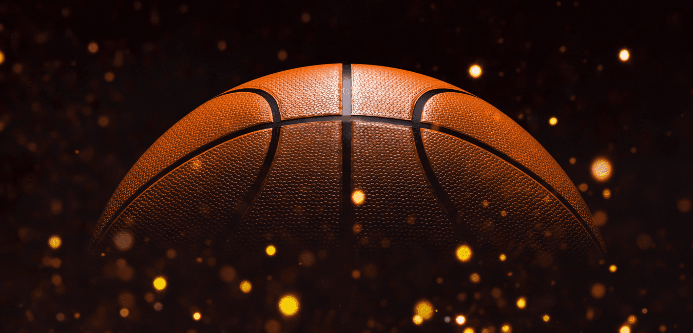 Nahaufnahme eines Basketballs vor einem dunklen Hintergrund mit glitzernden Lichtpunkten.