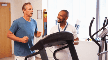 Ein Mann ist auf dem Laufband, der andere steht daneben