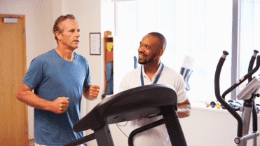 Ein Mann ist auf dem Laufband, der andere steht daneben