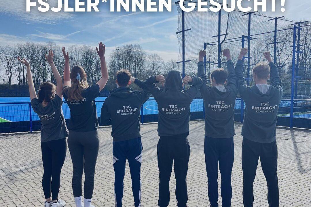 Gruppe von fünf Personen in Sweatshirts, die mit erhobenen Händen auf einem Sportgelände stehen. Text: „FSJler*innen gesucht!“