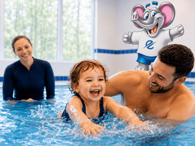L&auml;chelnde Familie im Schwimmbecken mit einem Kind, das im Wasser planscht, w&auml;hrend Erwachsene zuschauen.