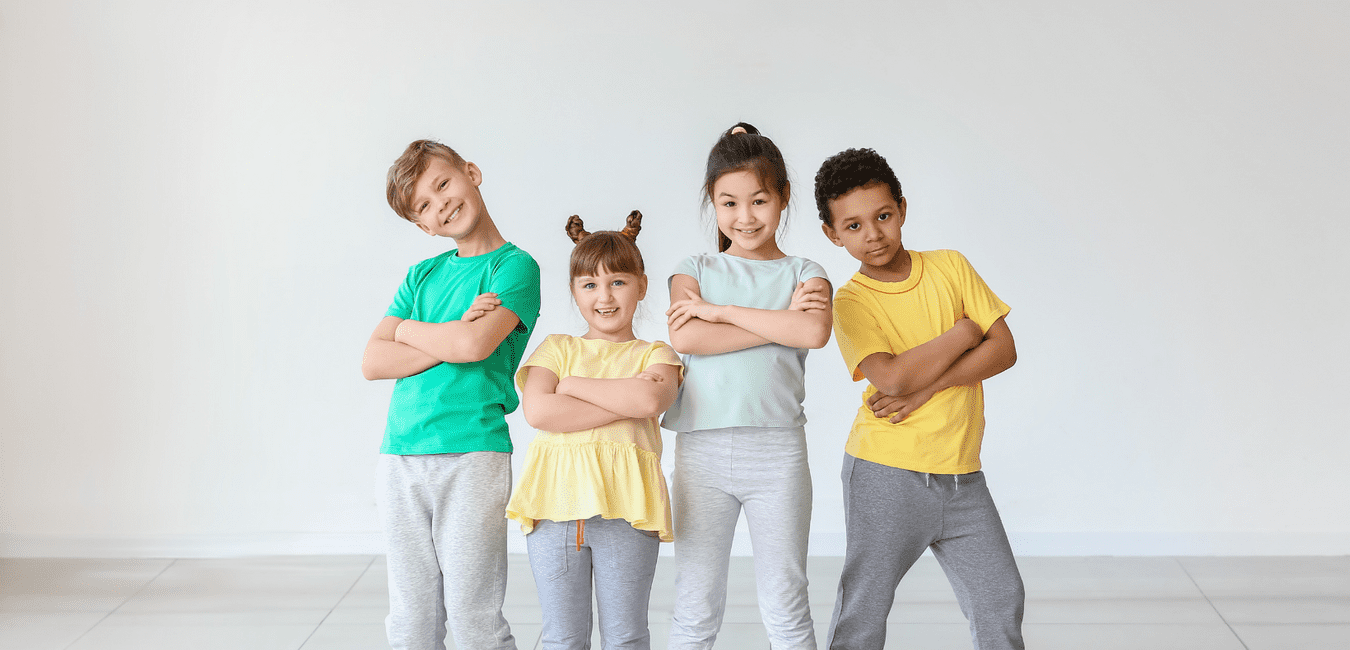 Vier Kinder in bunten T-Shirts stehen mit verschränkten Armen vor einer hellen Wand.