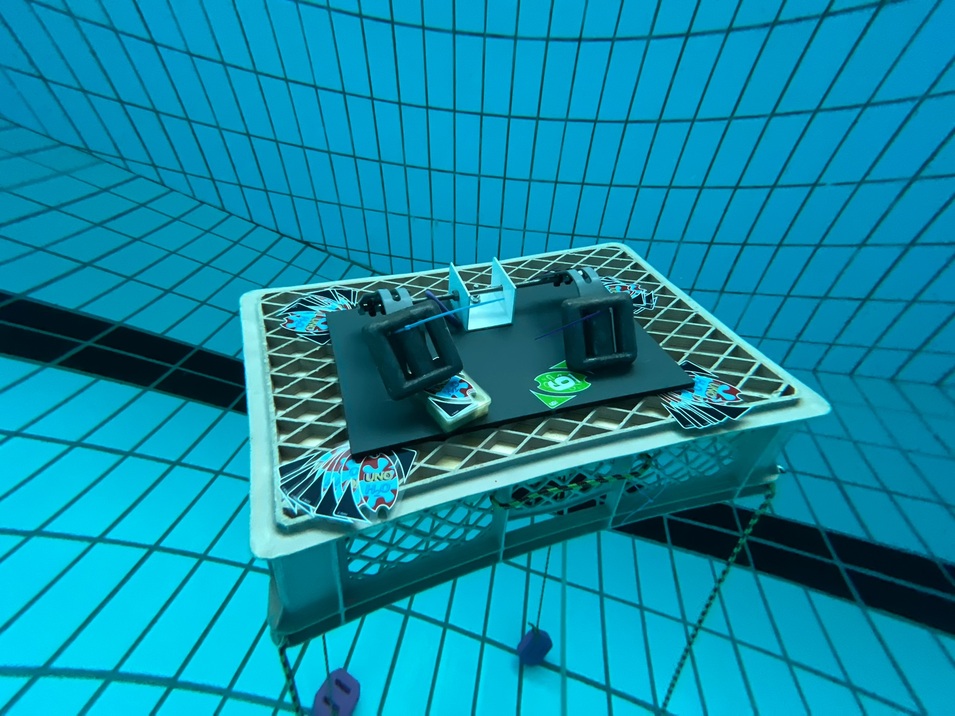 Tisch mit Spielutensilien und zwei Tischtennisschl&auml;gern auf dem Boden eines Schwimmbeckens.
