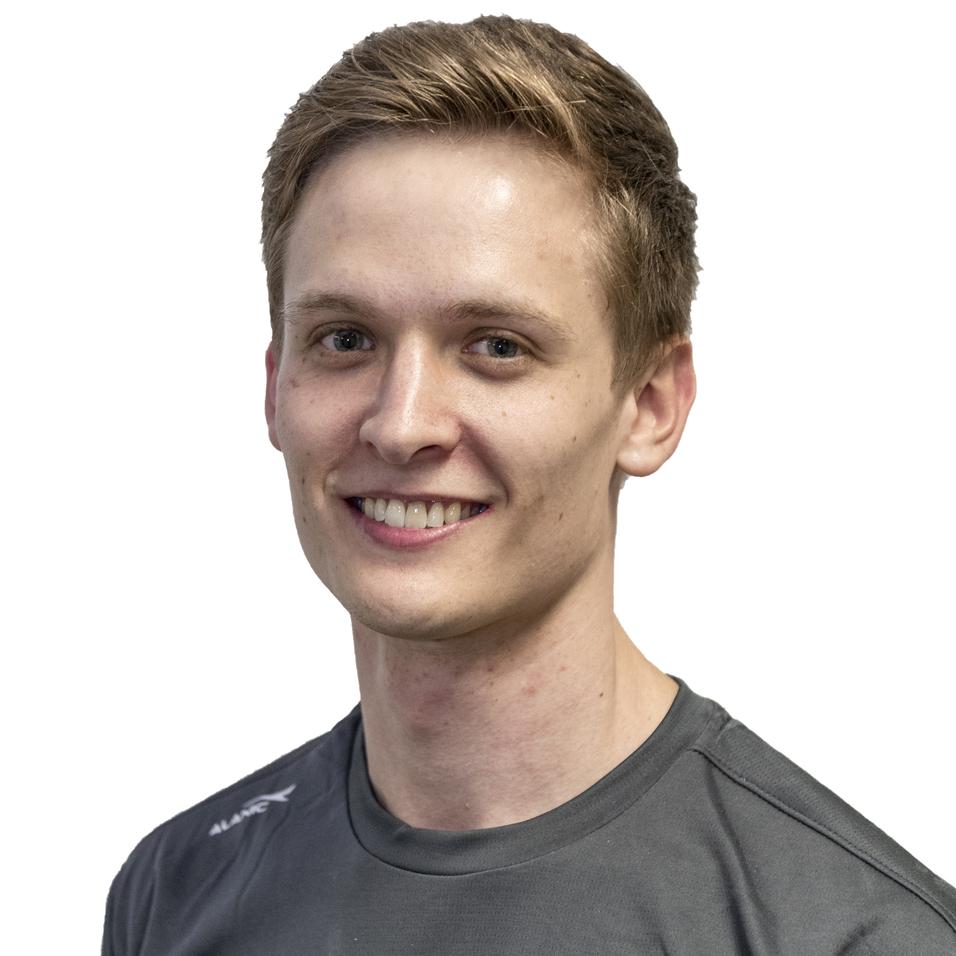 Junger Mann mit kurzem, braunem Haar, tr&auml;gt ein graues T-Shirt mit dem Schriftzug &bdquo;MUDDER&ldquo;, l&auml;chelnd vor wei&szlig;em Hintergrund.