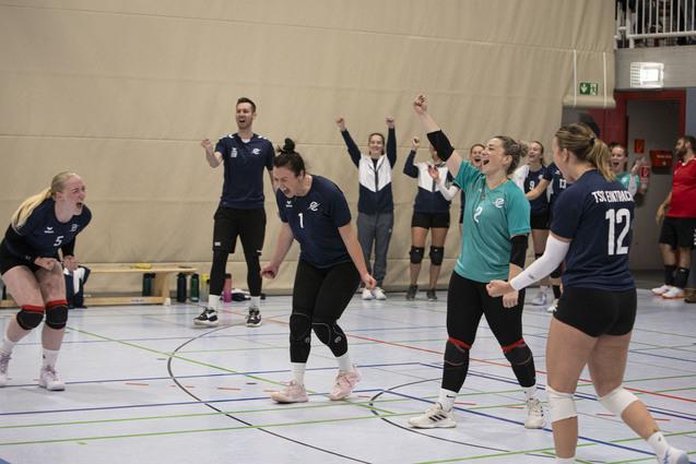 Teammitglieder jubeln auf einem Volleyballplatz nach einem Punktgewinn, mit sichtbarer Freude und Begeisterung.