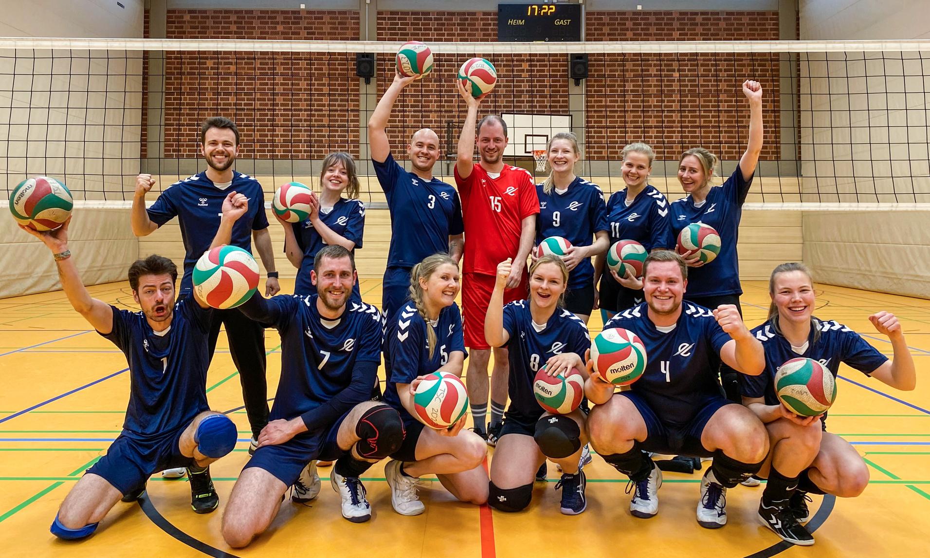 Mixed 6 Gruppe von Volleyballspielern in blauen Trikots, die fröhlich mit Bällen vor einem Netz posieren.