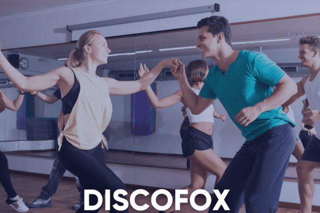 Tanzkurs-Teilnehmer &uuml;ben Discofox in einem lichtdurchfluteten Raum mit Spiegeln. Textinformationen zum Kursdatum sind eingeblendet.