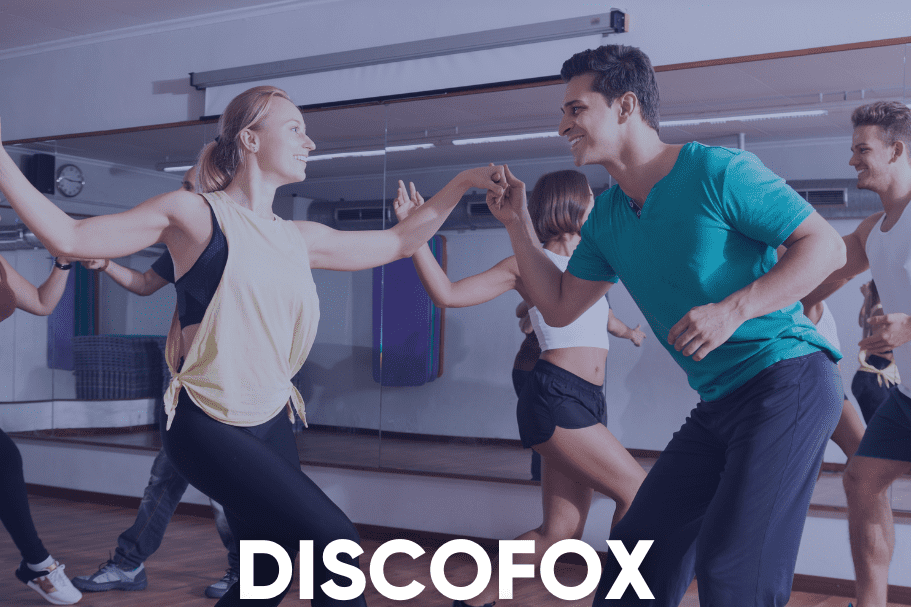Tanzkurs-Teilnehmer &uuml;ben Discofox in einem lichtdurchfluteten Raum mit Spiegeln. Textinformationen zum Kursdatum sind eingeblendet.