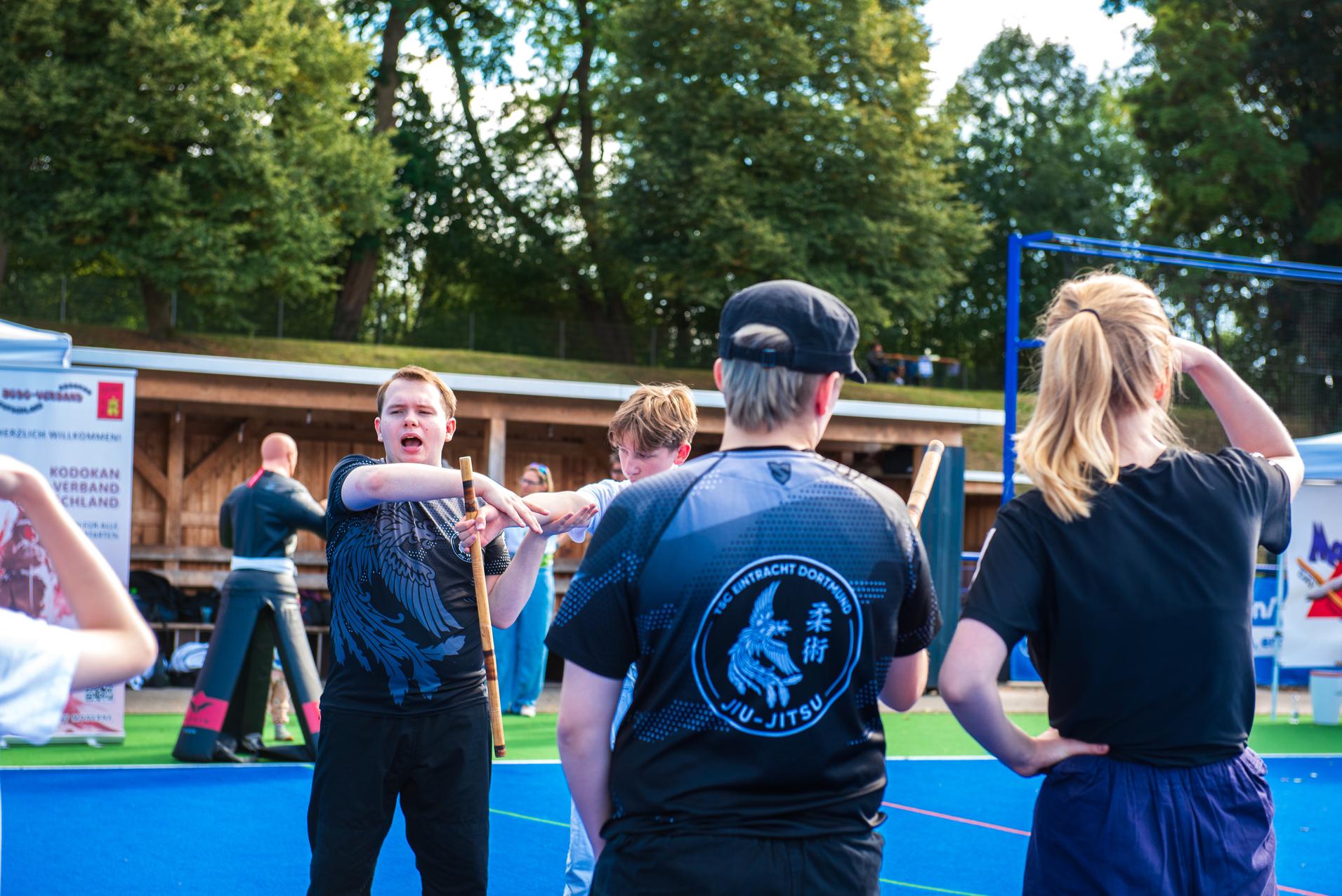 Gruppentraining in einem Freiluftbereich mit Kindern, die Techniken im Jiu-Jitsu demonstrieren.