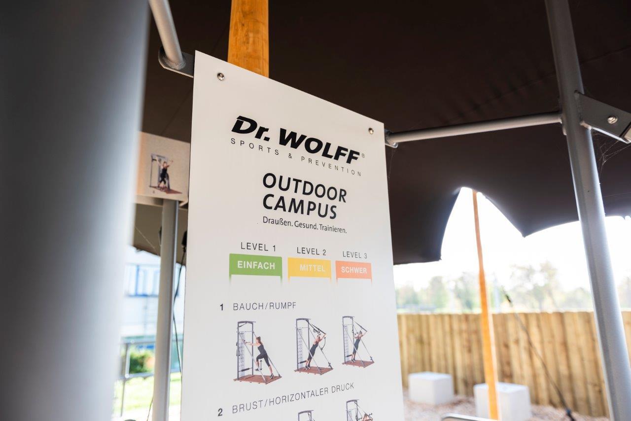 Infotafel des Dr. Wolff Outdoor Campus mit Trainingsleveln und &Uuml;bungen, umgeben von einem Sichtschutz.