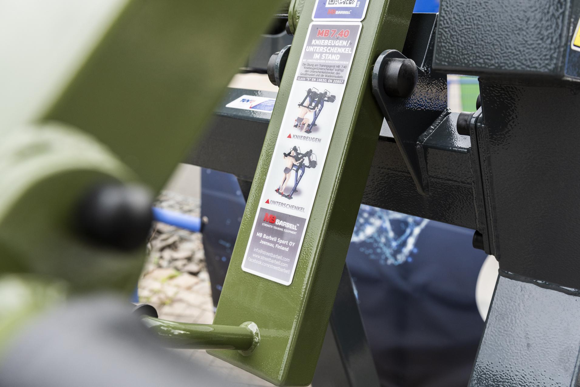 Nahaufnahme eines Bedienfelds an einem Fitnessger&auml;t mit Hinweisetikett und Anleitung in gr&uuml;ner Farbe.