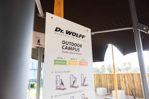 Infotafel des Dr. Wolff Outdoor Campus mit Trainingsleveln und &Uuml;bungen, umgeben von einem Sichtschutz.