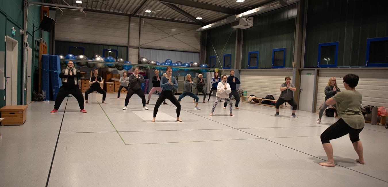 Gruppe von Personen in Sportkleidung bei einem Training in einer gro&szlig;en Turnhalle.