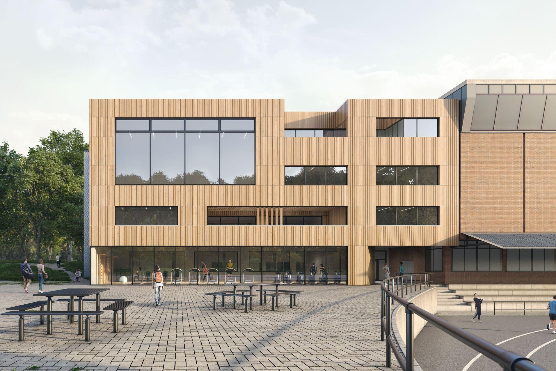 Moderne Schulgeb&auml;ude mit gro&szlig;en Fenstern, umgeben von B&auml;umen und einem Freiplatz mit Sitzgelegenheiten.